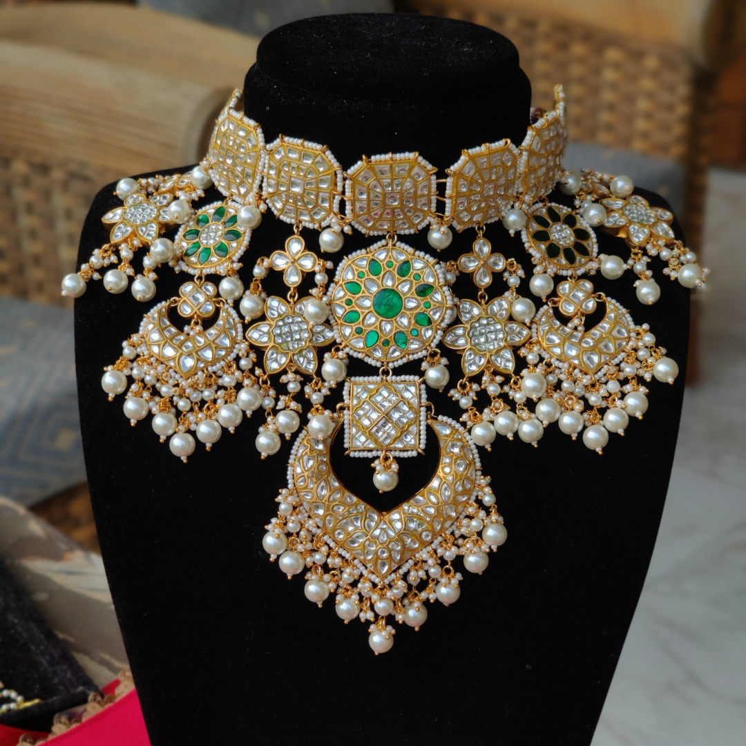 Kundan necklace studded with emerald stones and pearl drops.
